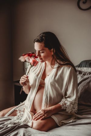 Artistic pregnancy photography with white flowing robe and dramatic shadows.
