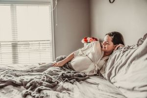 Lifestyle maternity photography with soft natural light from window.