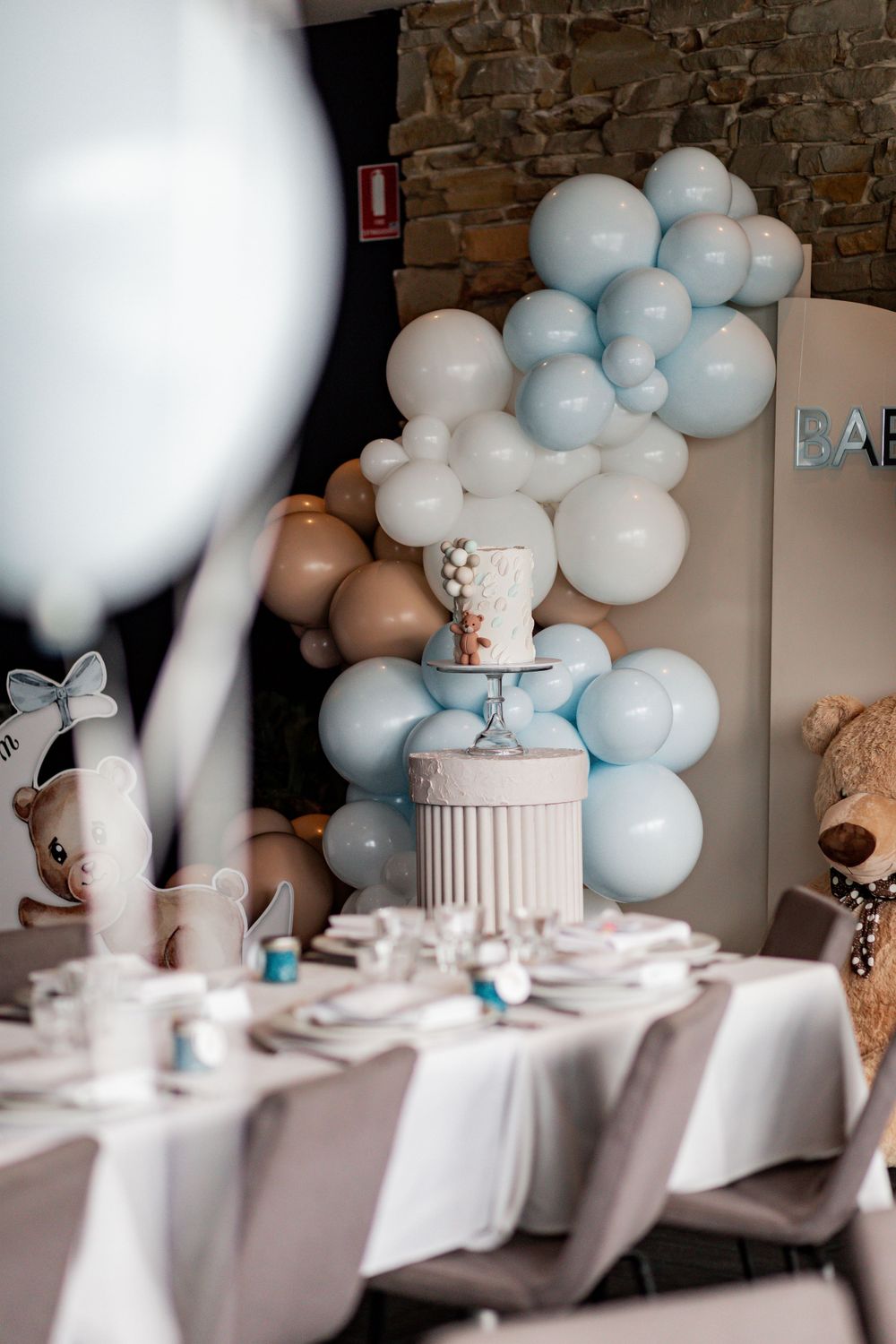Elegant baby shower table setting with blue and white balloon decorations and centerpiece.