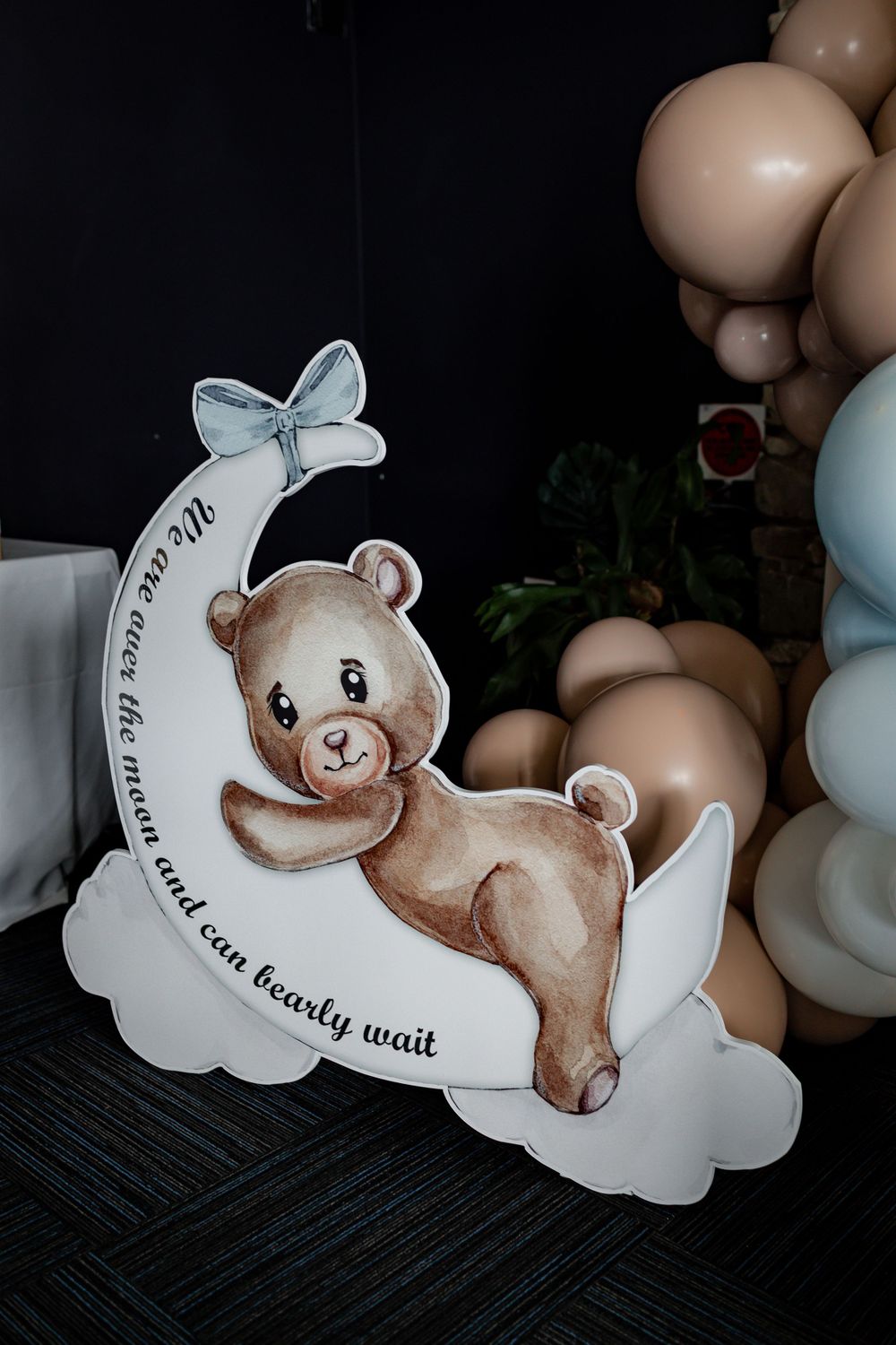 Cute cartoon bear illustration on a cloud with blue bow and decorative text.
