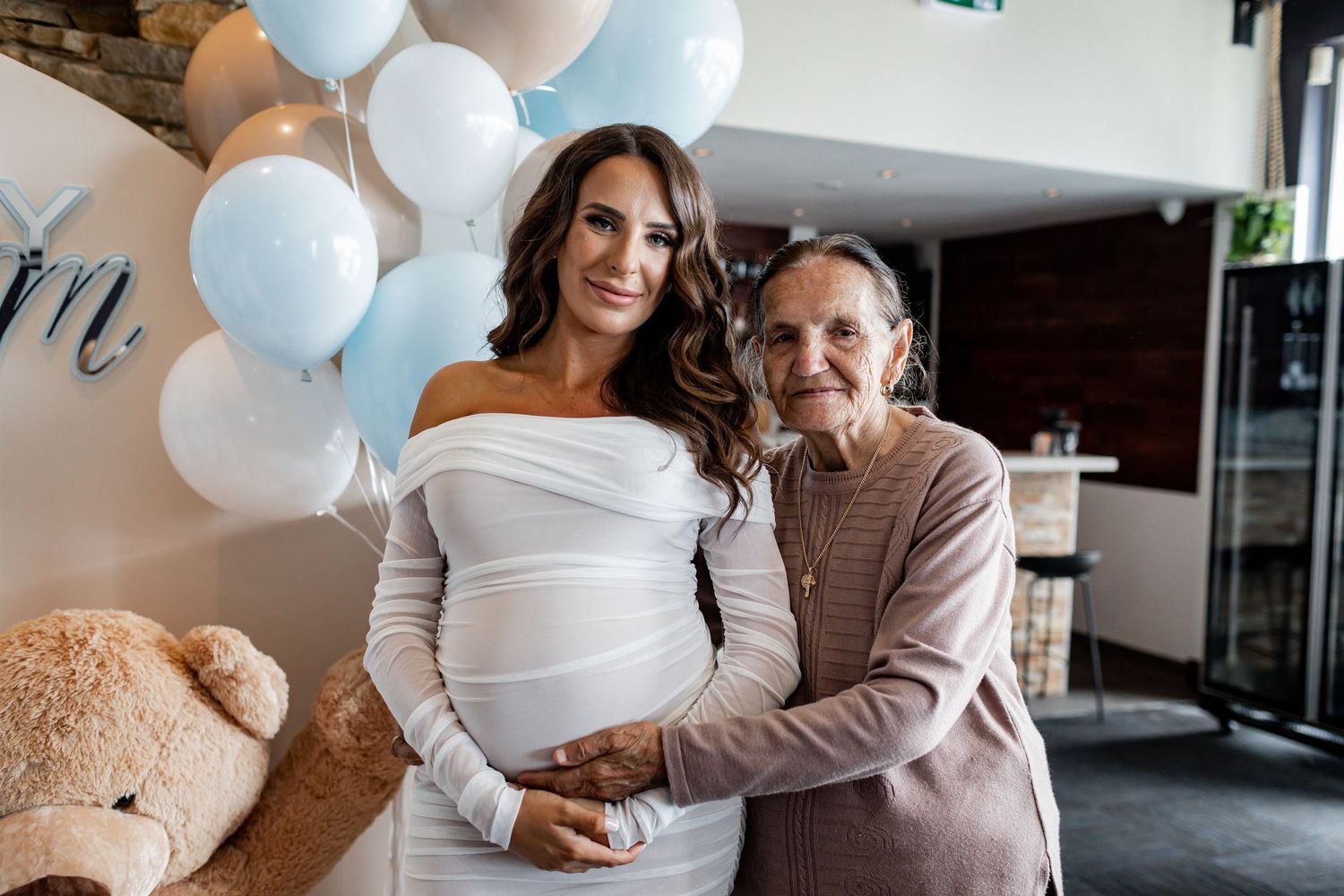 Two people sharing a tender moment at a baby shower with blue balloon decorations.
