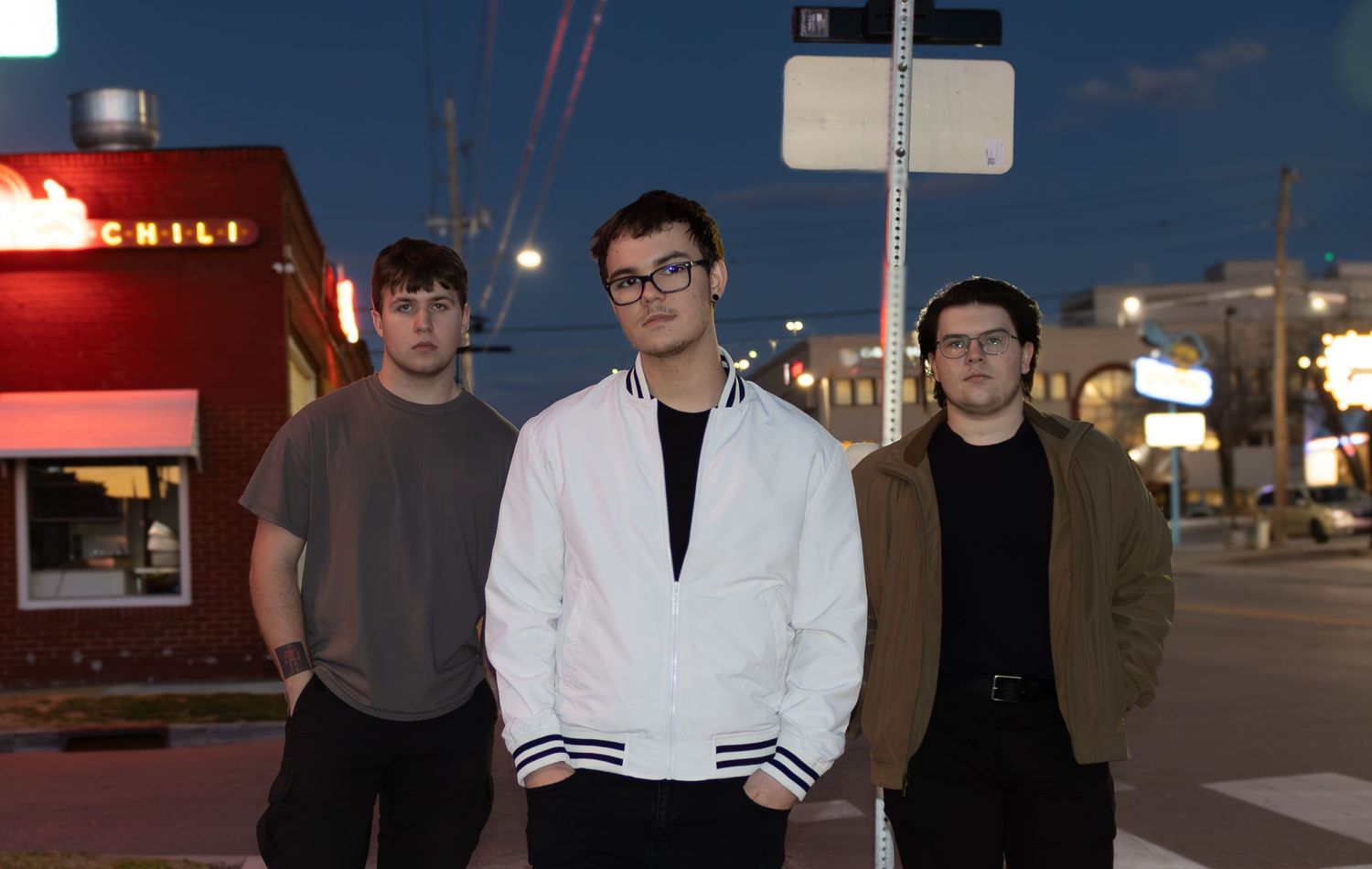 Studio portrait of music band members standing together in casual attire at night.