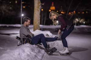a woman helping a man put on skates