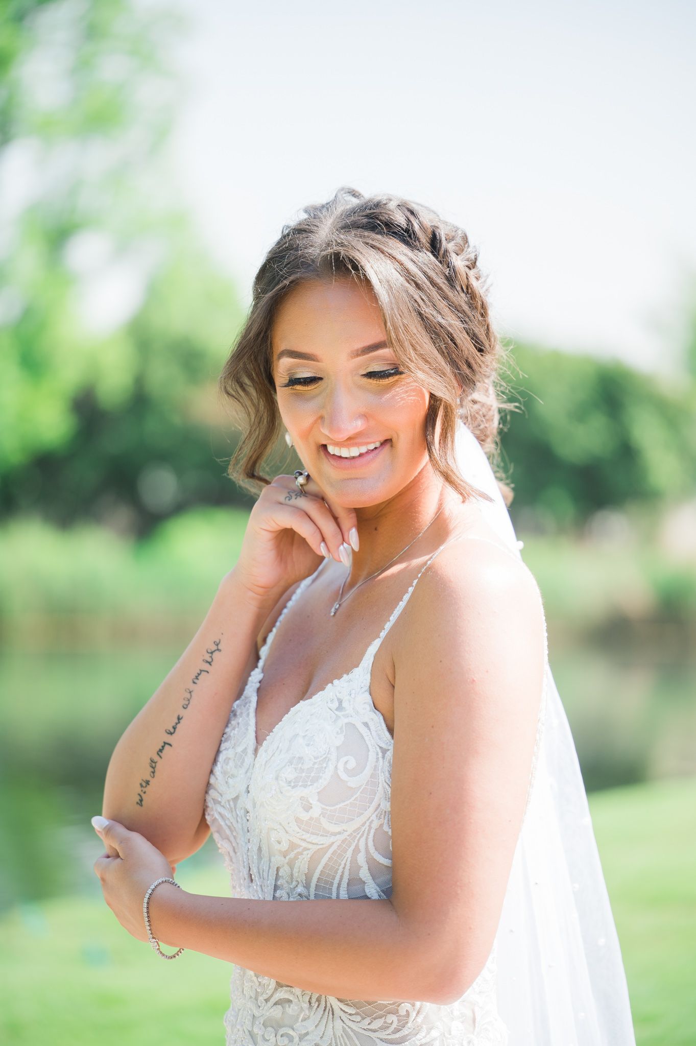 Smiling bride showcasing her beautiful arm tattoo.