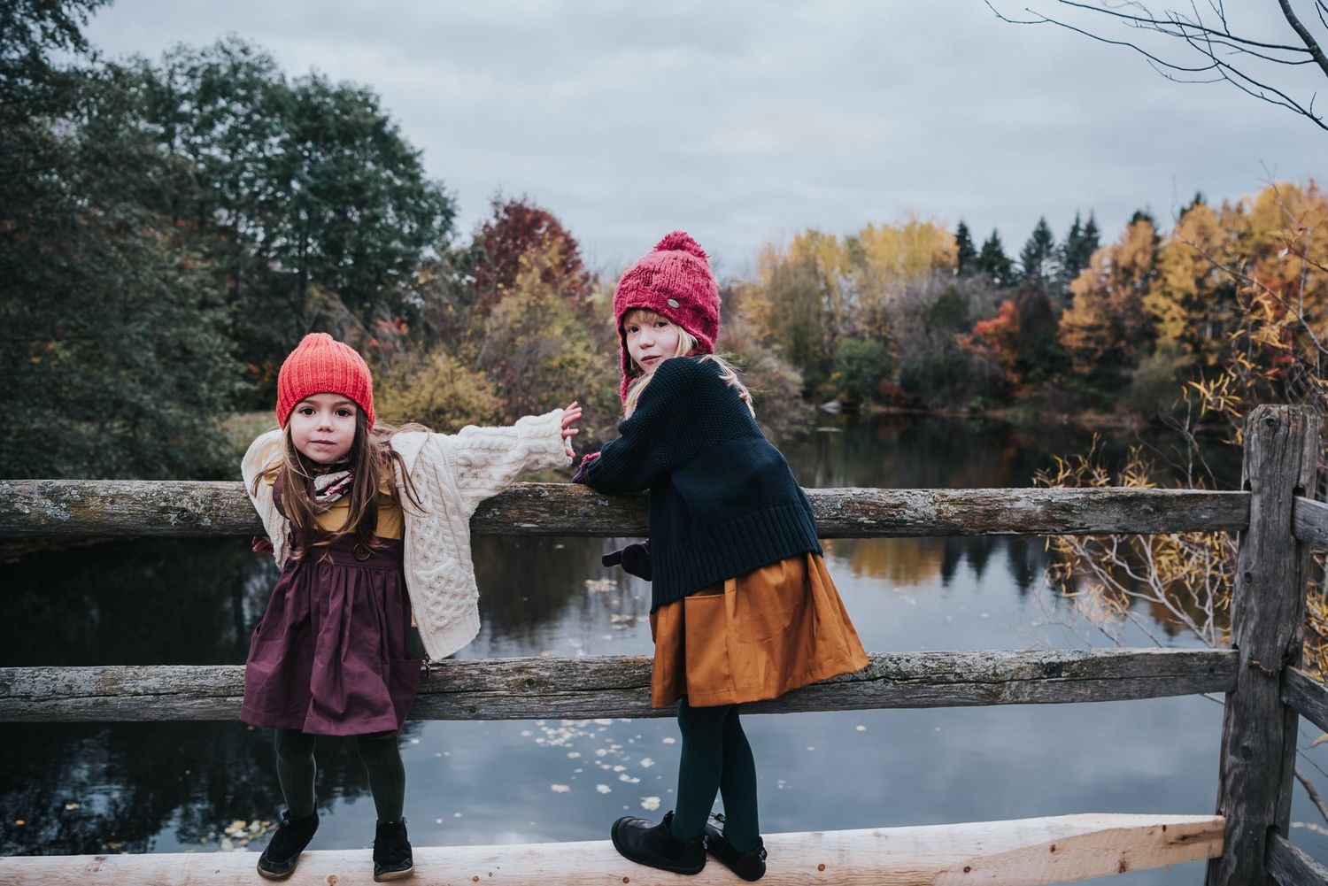 Girls wearing Fall clothes with Fall trees in the background and a pond.