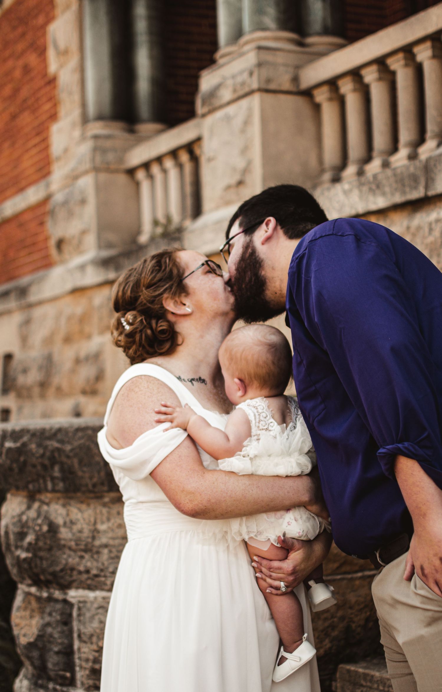 Family sharing intimate moment on stone steps of historic building.
