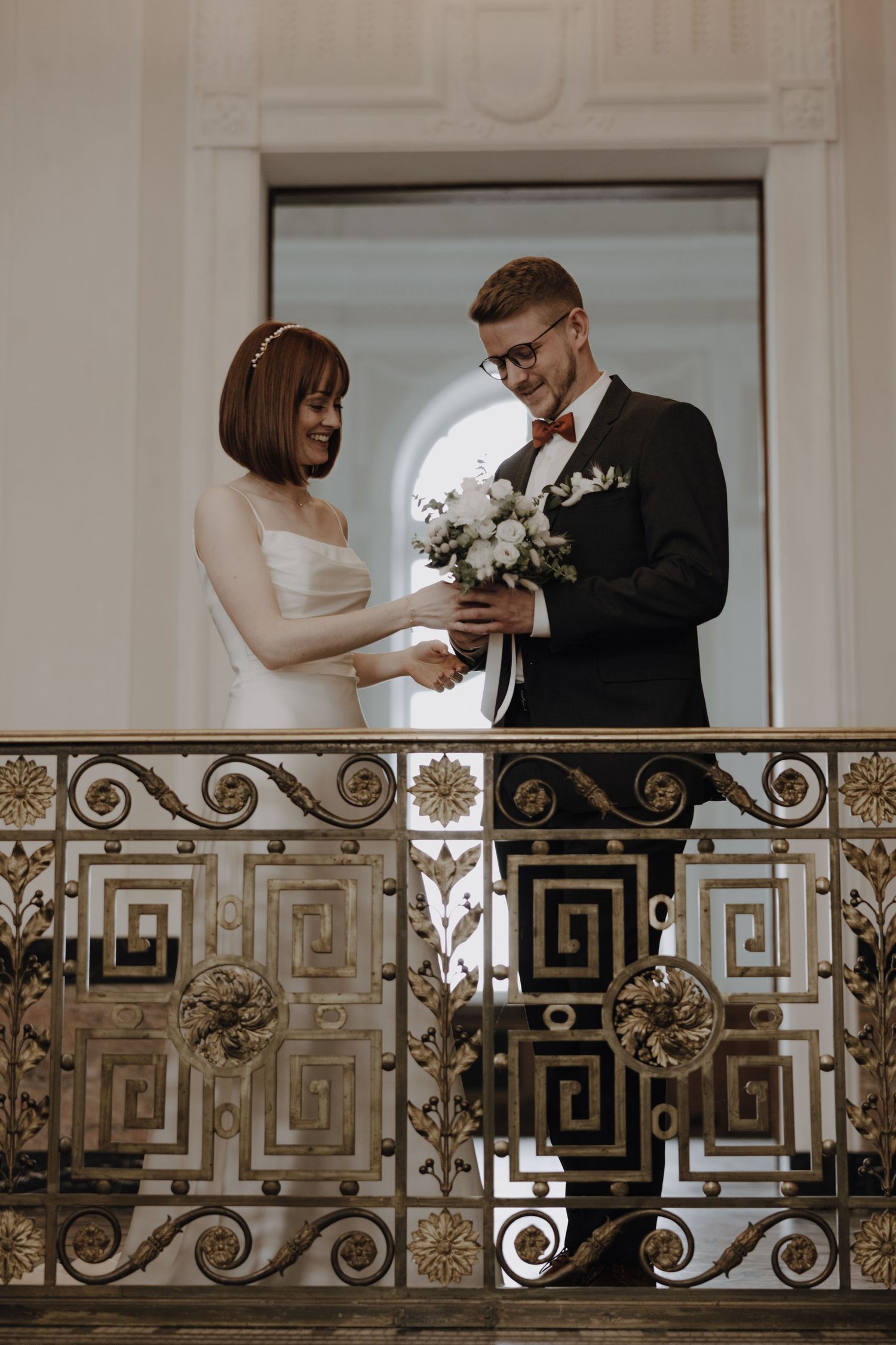 Couple shares tender moment on ornate balcony with geometric railing design.