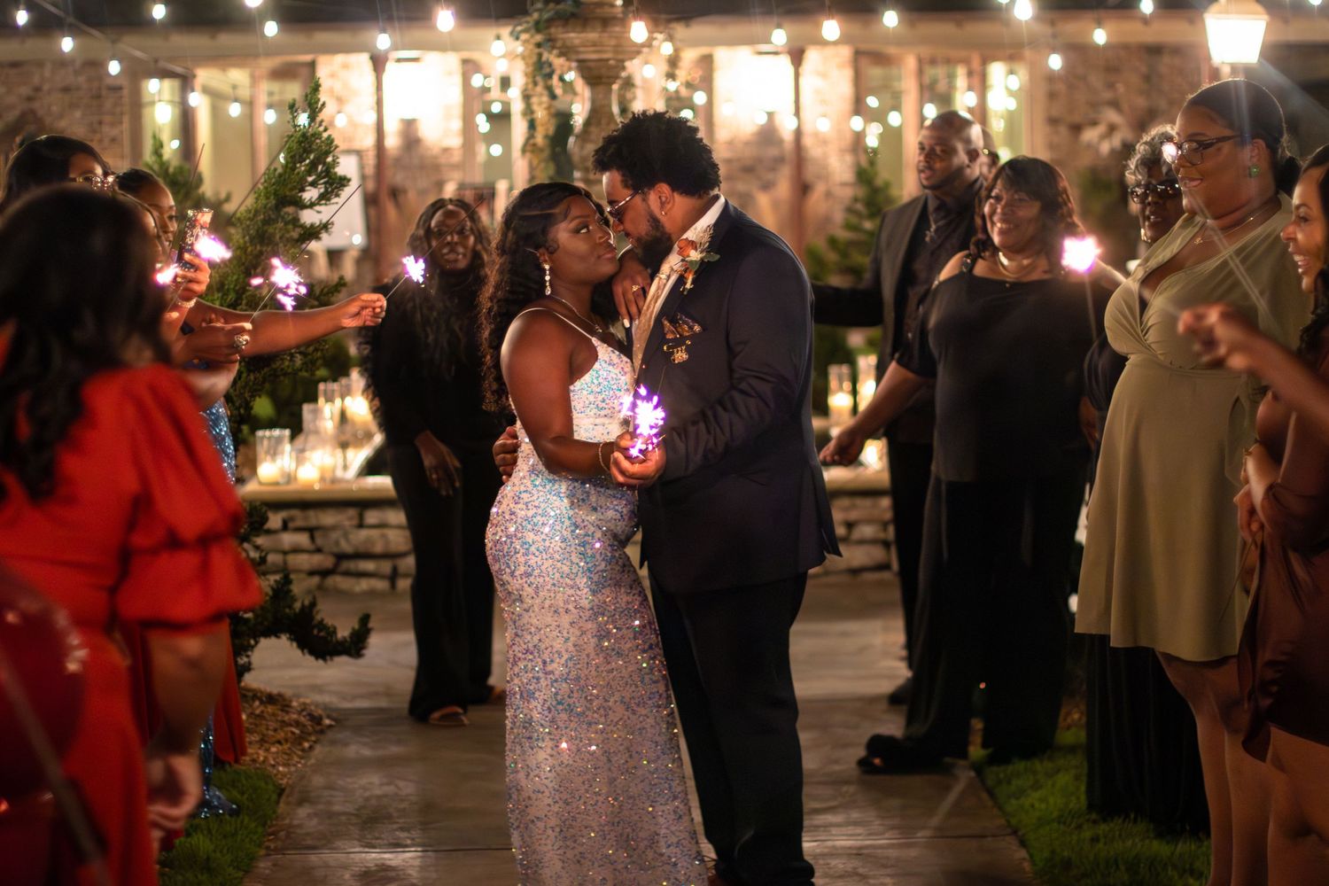 Romantic evening dance under string lights at an outdoor wedding reception.