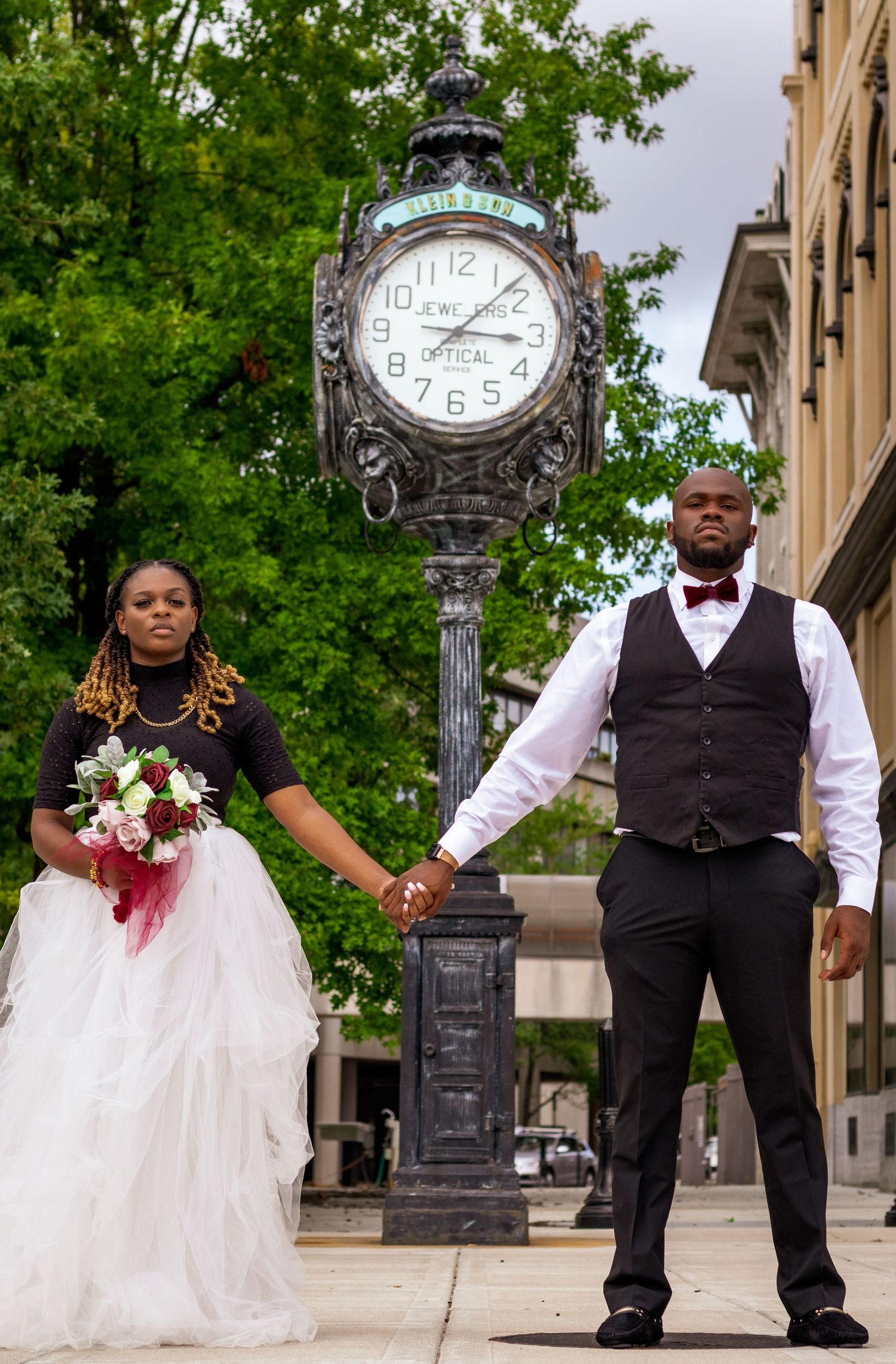 Newly weds posing in front of a downtown Montgomery, AL clock tower.