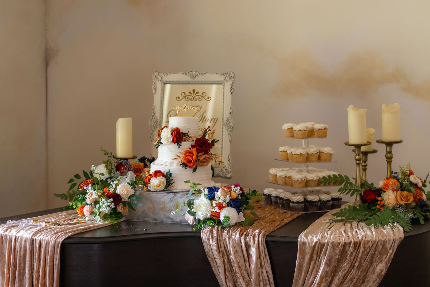 Wedding dessert table with ornate mirror, candles, and floral arrangements.