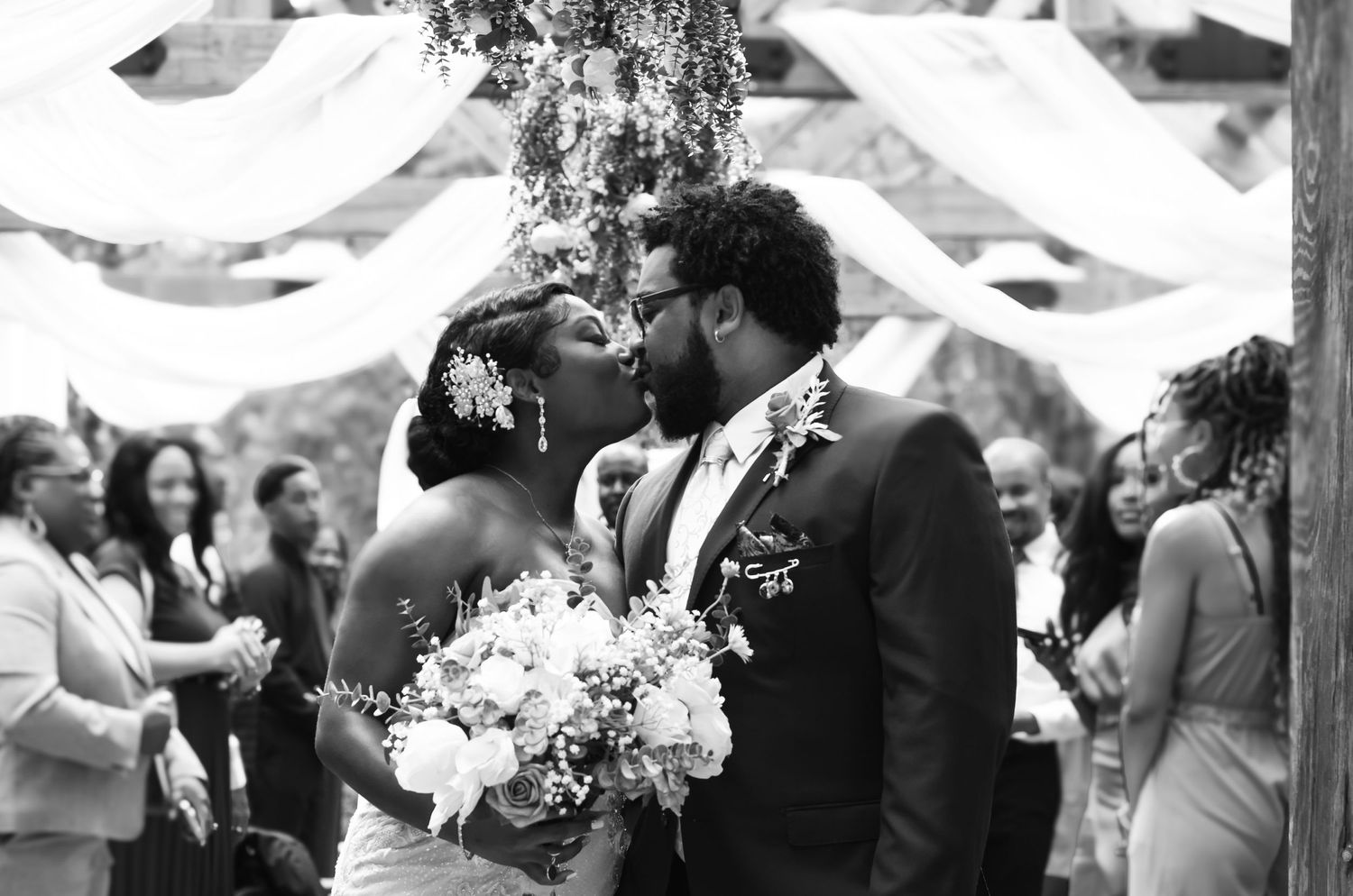 Intimate wedding ceremony moment beneath decorative fabric draping.