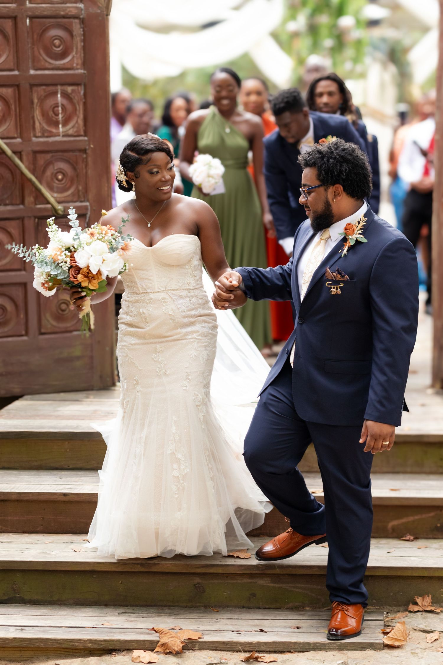 Newlyweds descending stone steps in formal wedding attire.