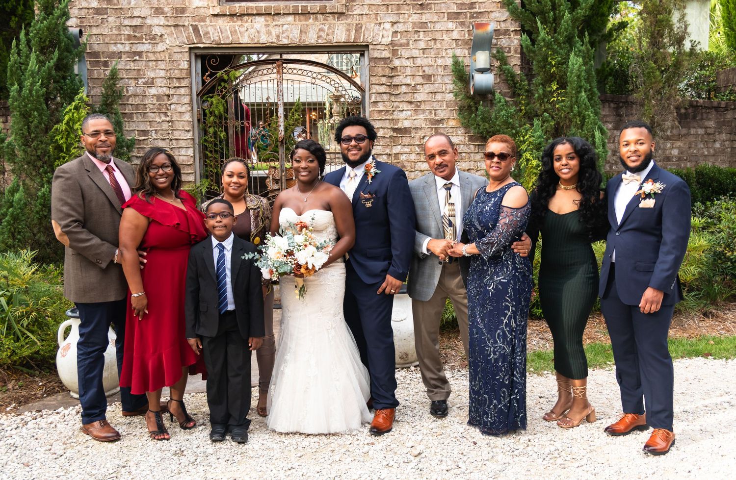 Wedding party group photo in front of brick wall with formal attire.