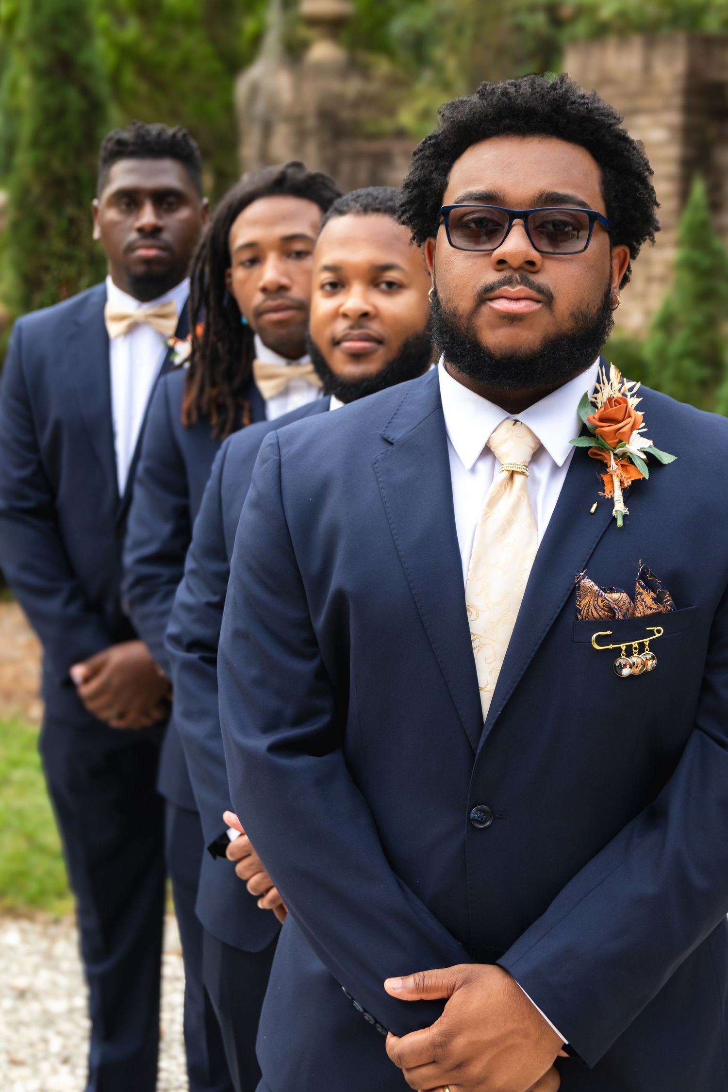 Groomsmen in navy suits lined up for formal wedding portrait.