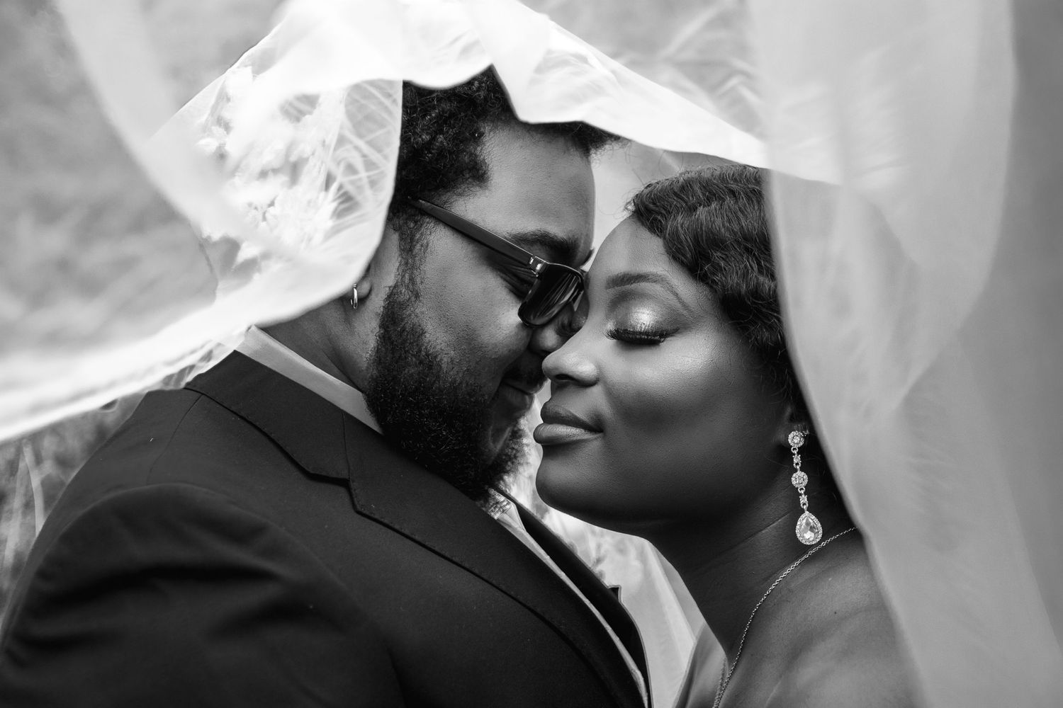 Black and white portrait of newlyweds sharing an intimate moment under the veil.