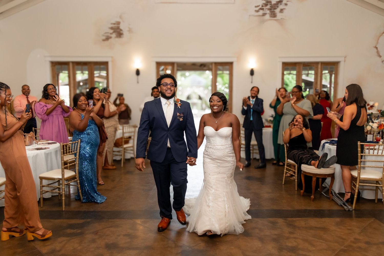Newlyweds make their grand entrance into the reception as guests cheer and celebrate.