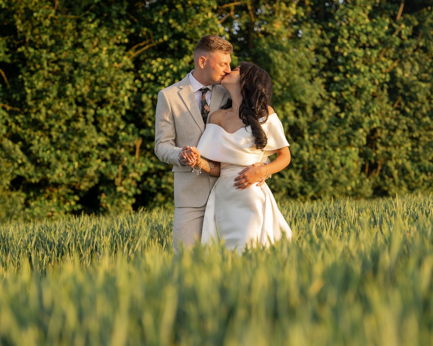 Couple shares romantic moment while standing in golden wheat field at sunset.