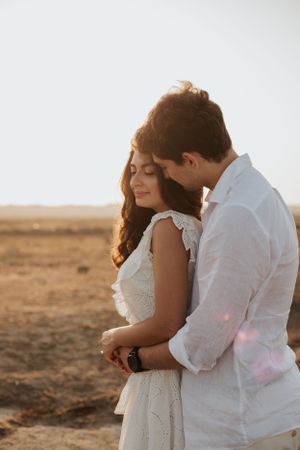 Tender embrace captured in warm sunlight with desert scenery.