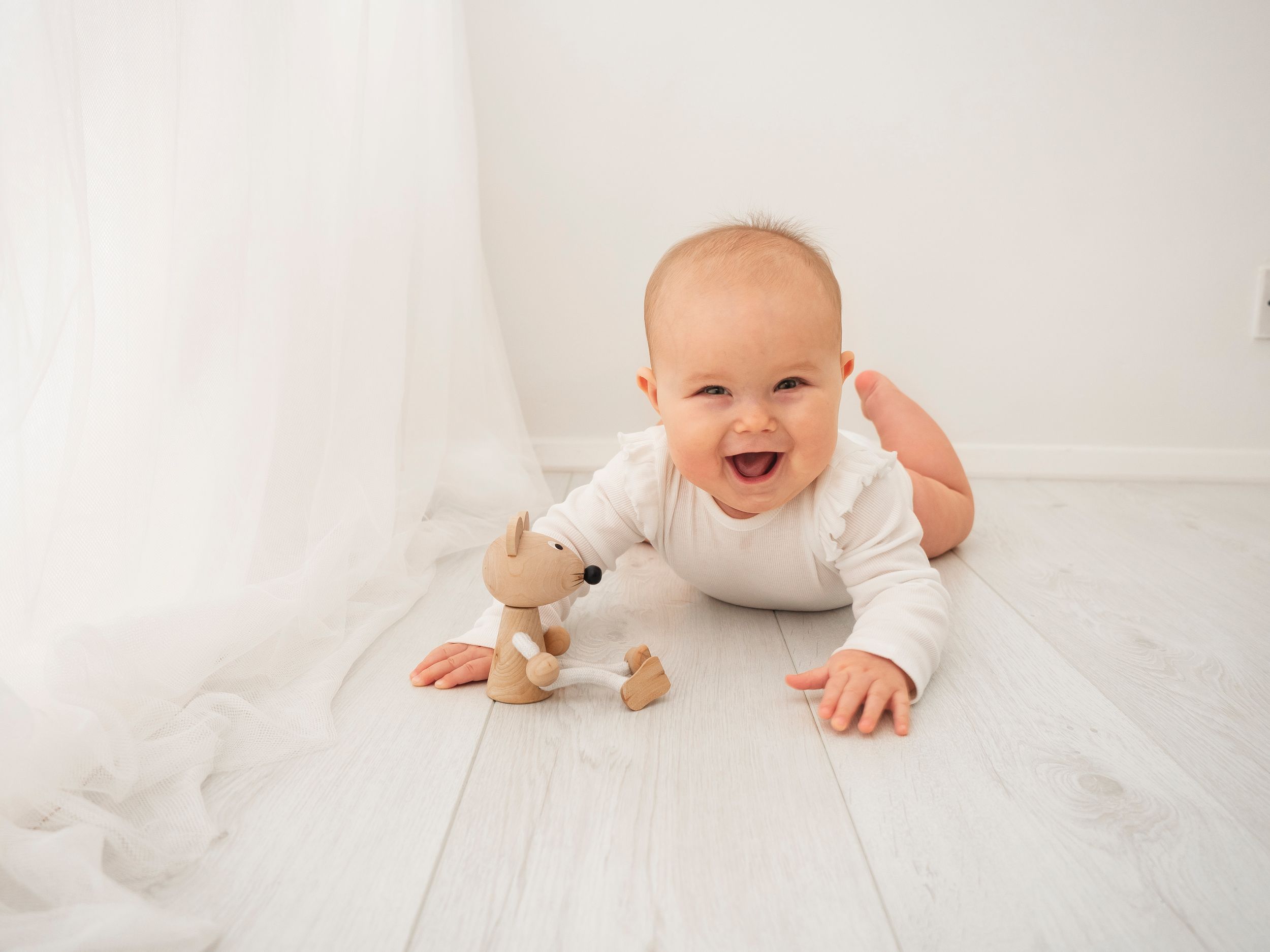 baby laying on tummy smiles and laughs during a photoshoot in Didcot