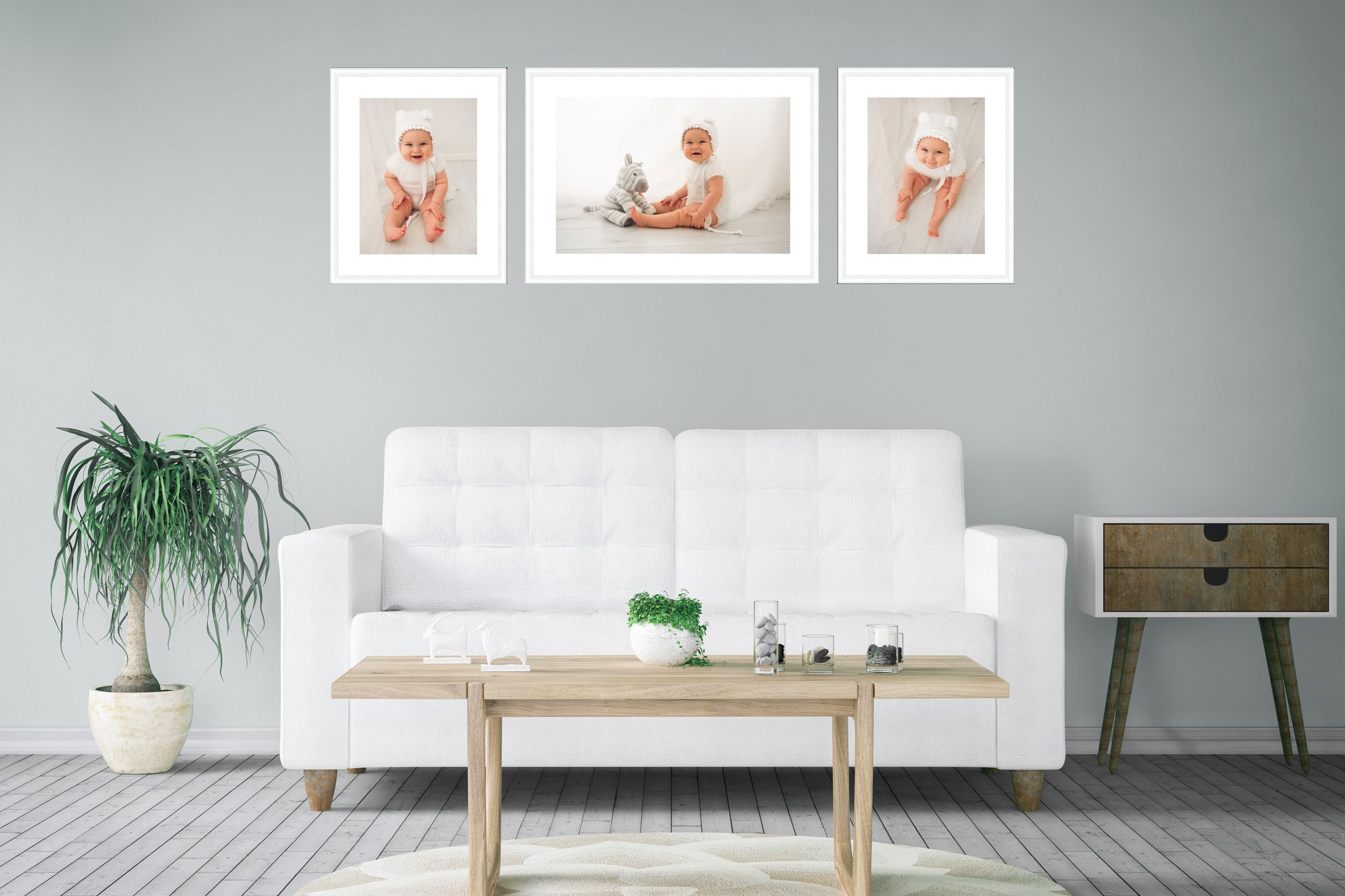 A set of three framed photos hung above a white sofa, displaying a 7 month babies photoshoot.
