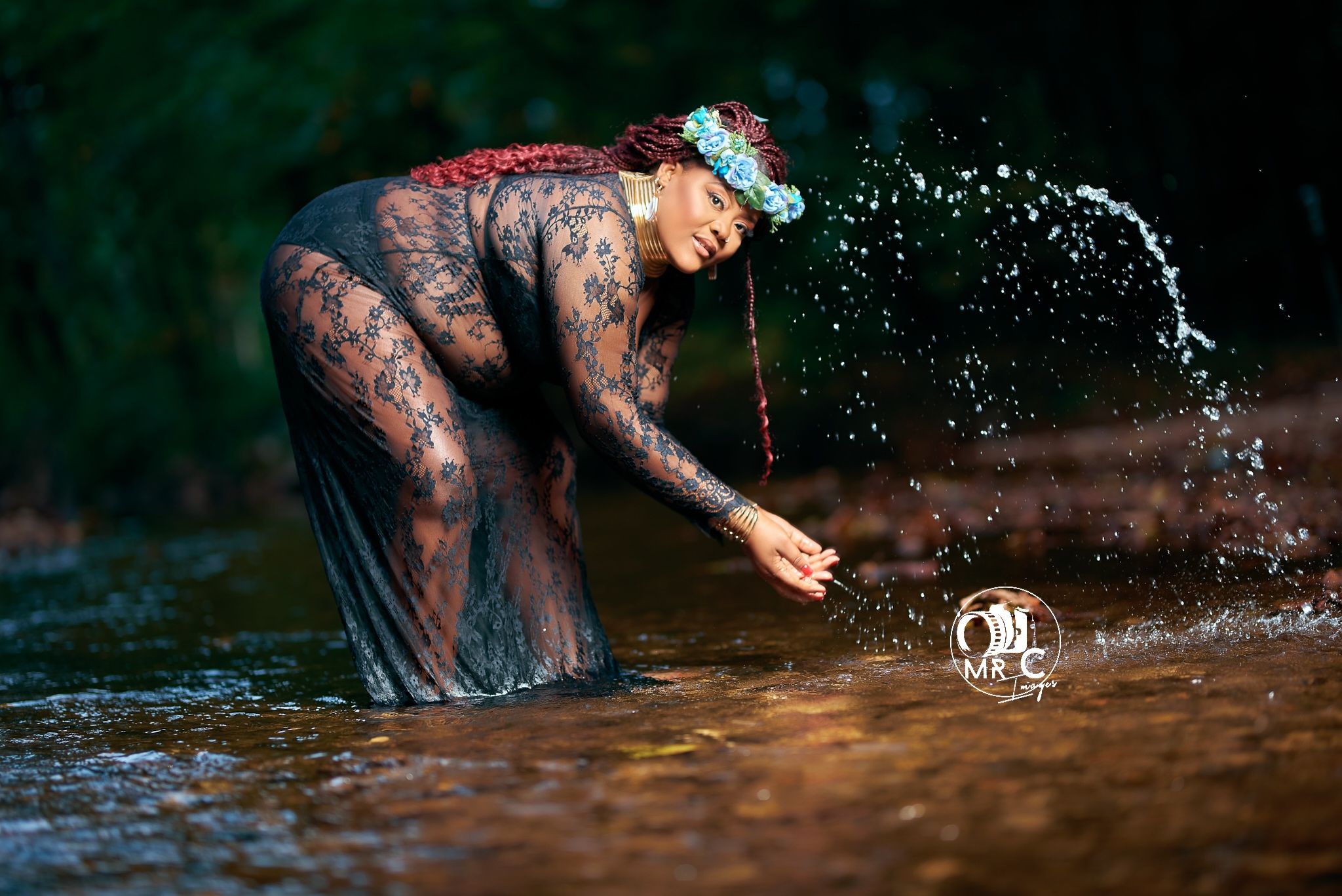 Creative maternity photo with subject splashing water in sheer black dress.