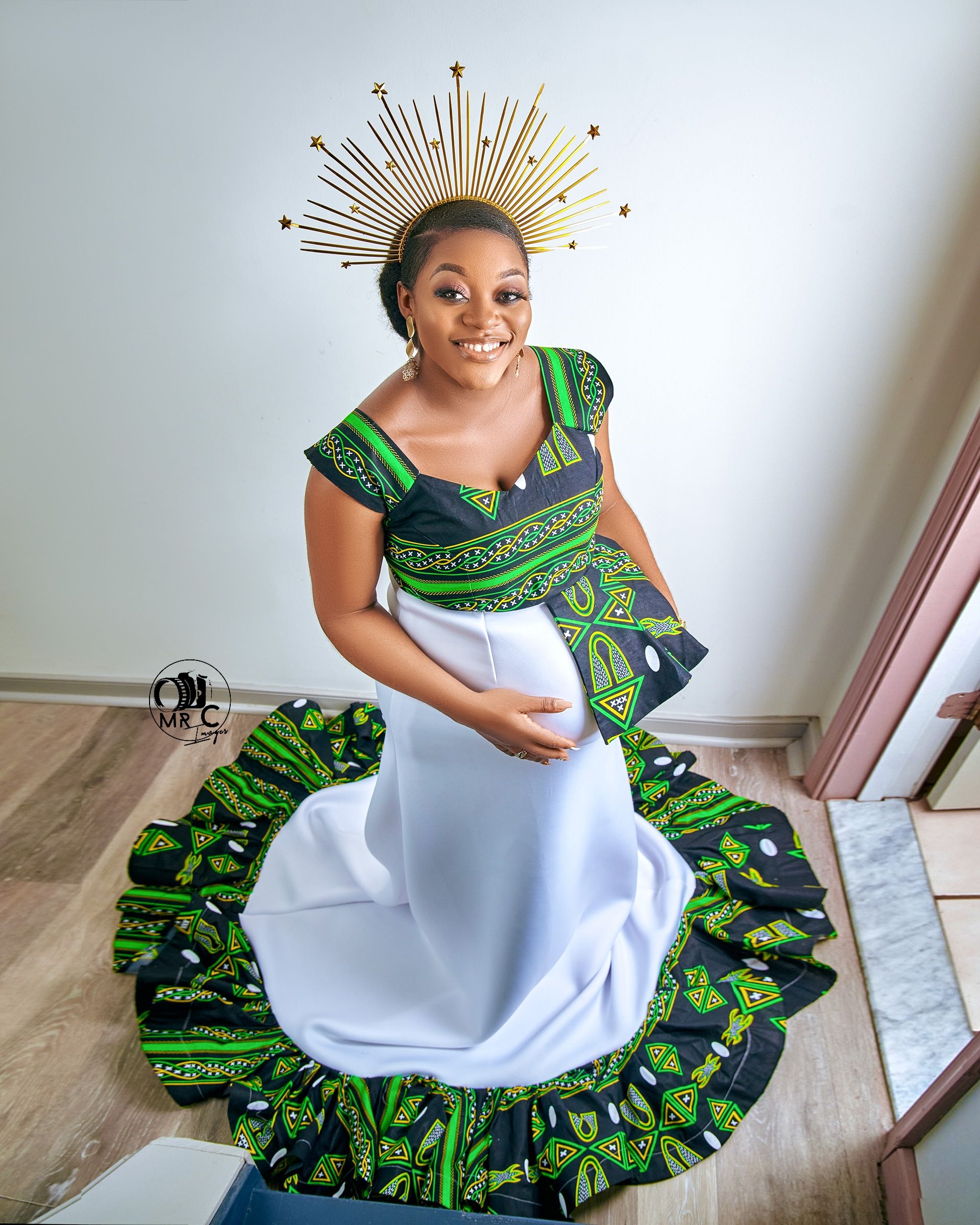 Maternity portrait featuring white dress with African print trim and golden sunburst crown.