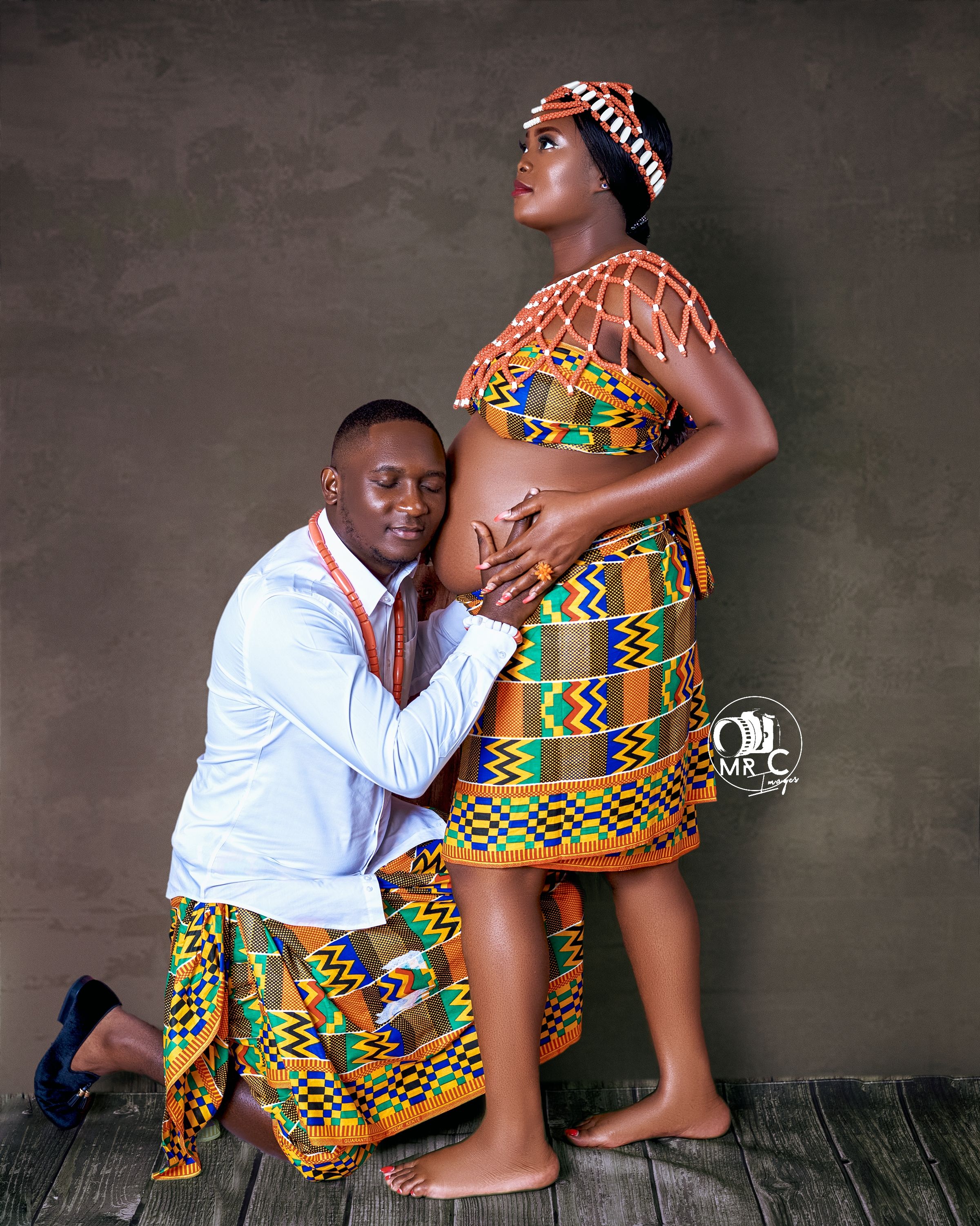 A traditional African print maternity photoshoot featuring colorful kente cloth designs.