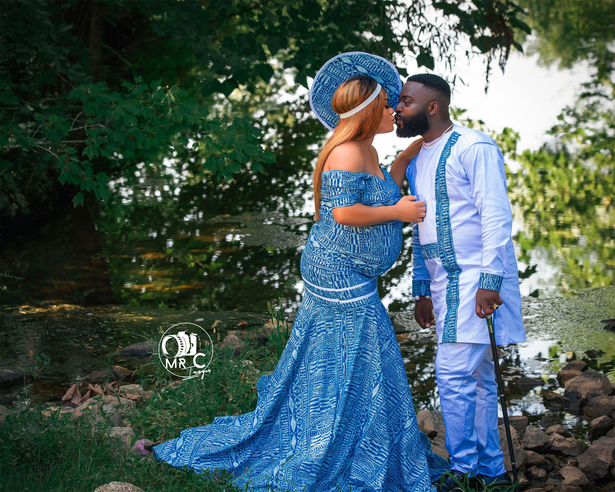 A couple embracing outdoors, wearing formal blue sequined gown and white suit.