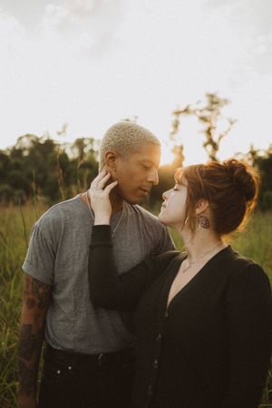 An intimate moment between a couple in a field during golden hour sunset.