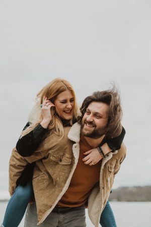 A joyful piggyback ride filled with laughter against a cloudy backdrop.
