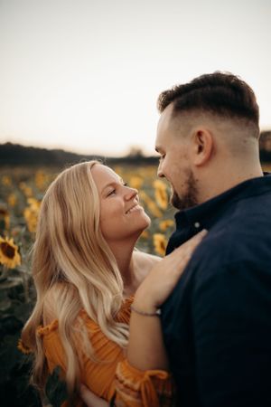 Romantic couple portrait in sunflower field during golden hour.