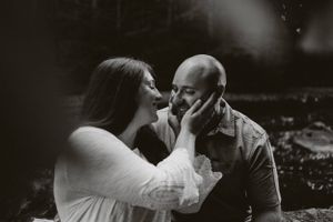 An intimate black and white portrait of a couple sharing a romantic moment outdoors.