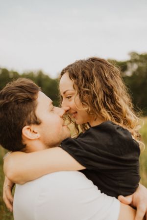 A romantic couple shares an intimate embrace in a sunlit outdoor setting.
