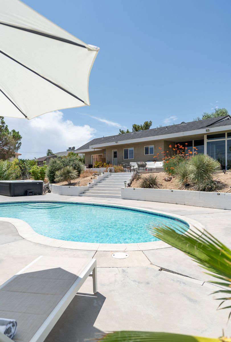 Curved swimming pool with white umbrellas and desert landscape views.