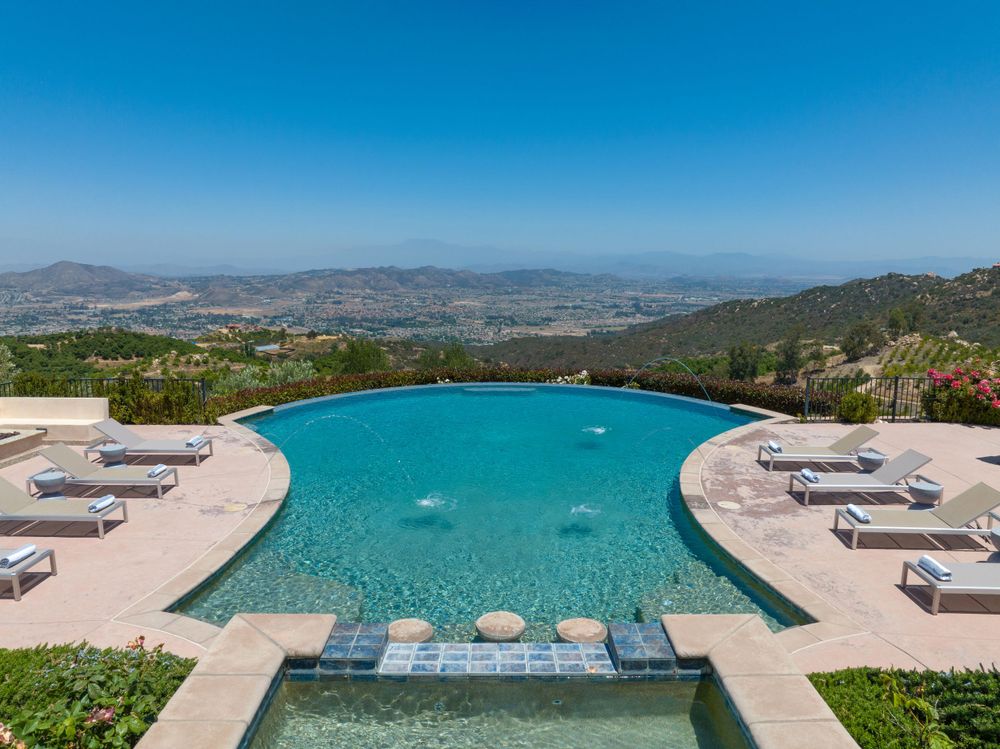 Luxurious infinity pool with panoramic mountain views and white lounge chairs.
