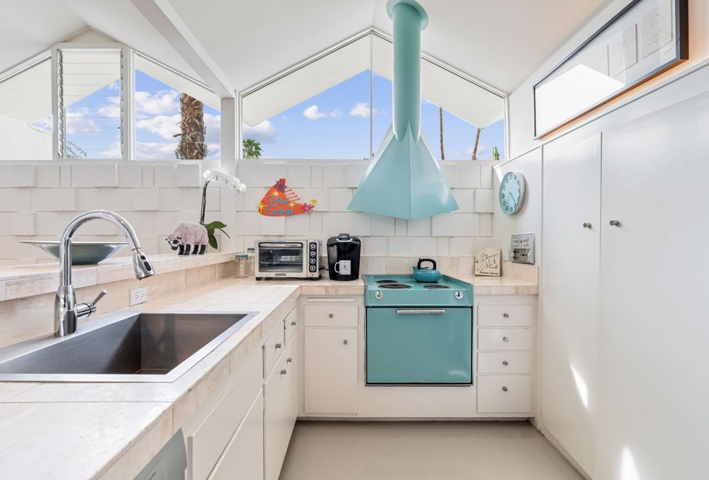 Retro-inspired kitchen with turquoise appliances, white cabinets, and pitched ceiling with natural light.