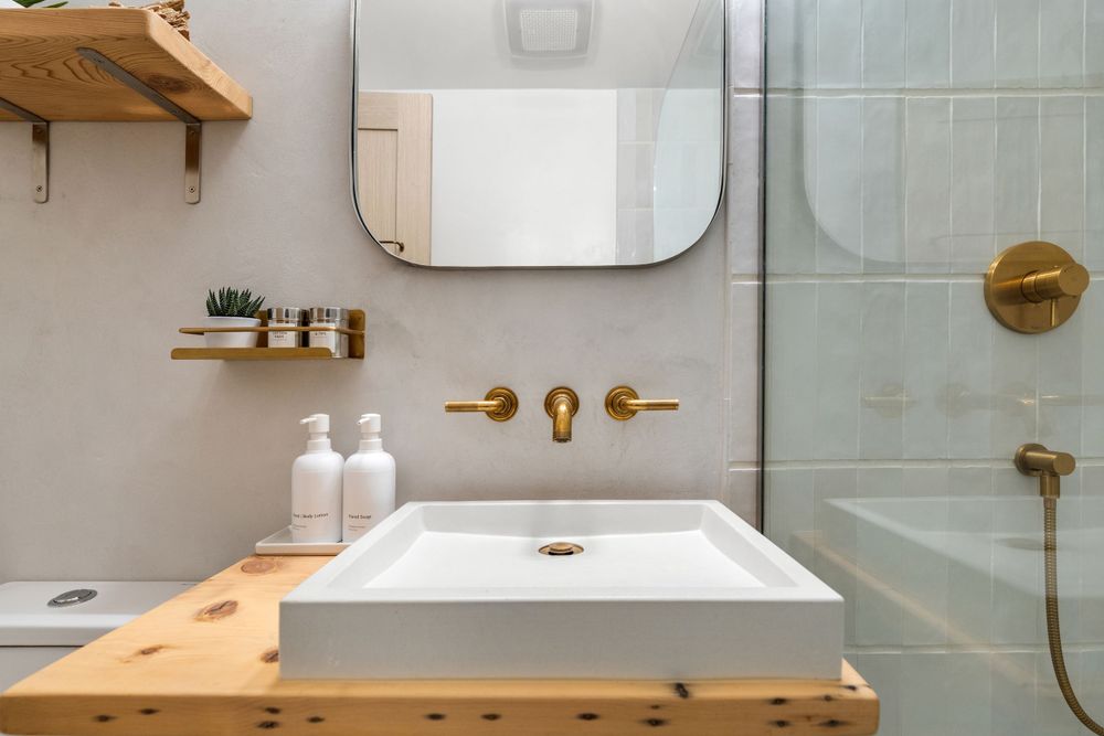 Contemporary bathroom with floating vanity, white fixtures, and brass accents.