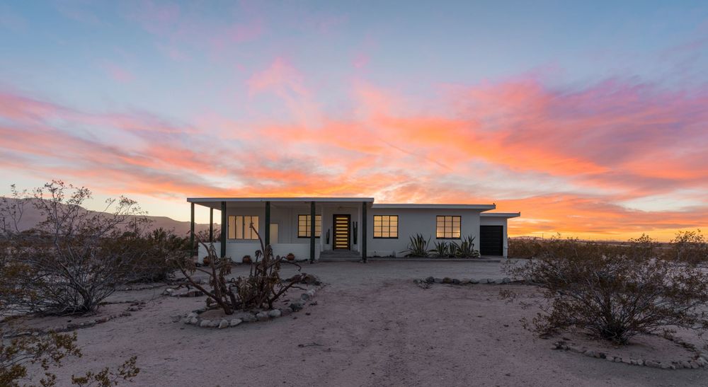 Stunning desert sunset panorama with pink and orange clouds stretching across the horizon.