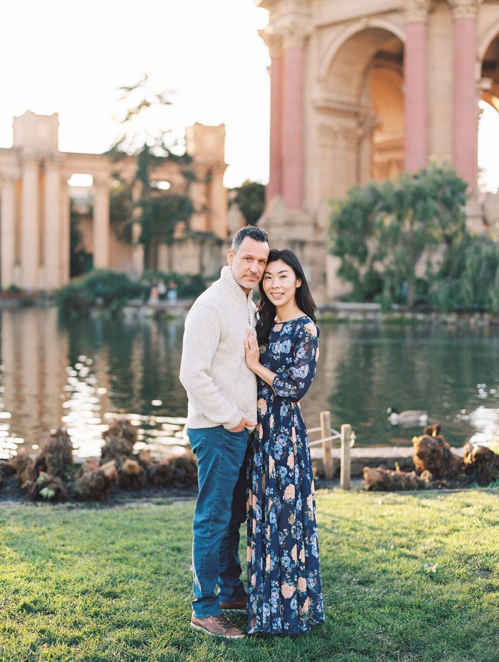Romantic couple standing by reflecting pool at Palace of Fine Arts in San Francisco.