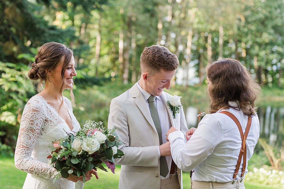 Groomswoman helps groom get ready for wedding during portraits