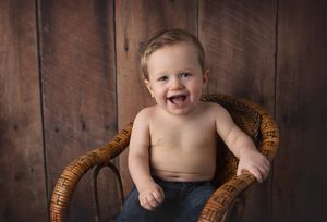 A happy expression while sitting in a woven wicker chair against rustic wooden planks.