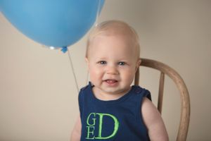 A delightful moment with a blue balloon and monogrammed navy outfit.