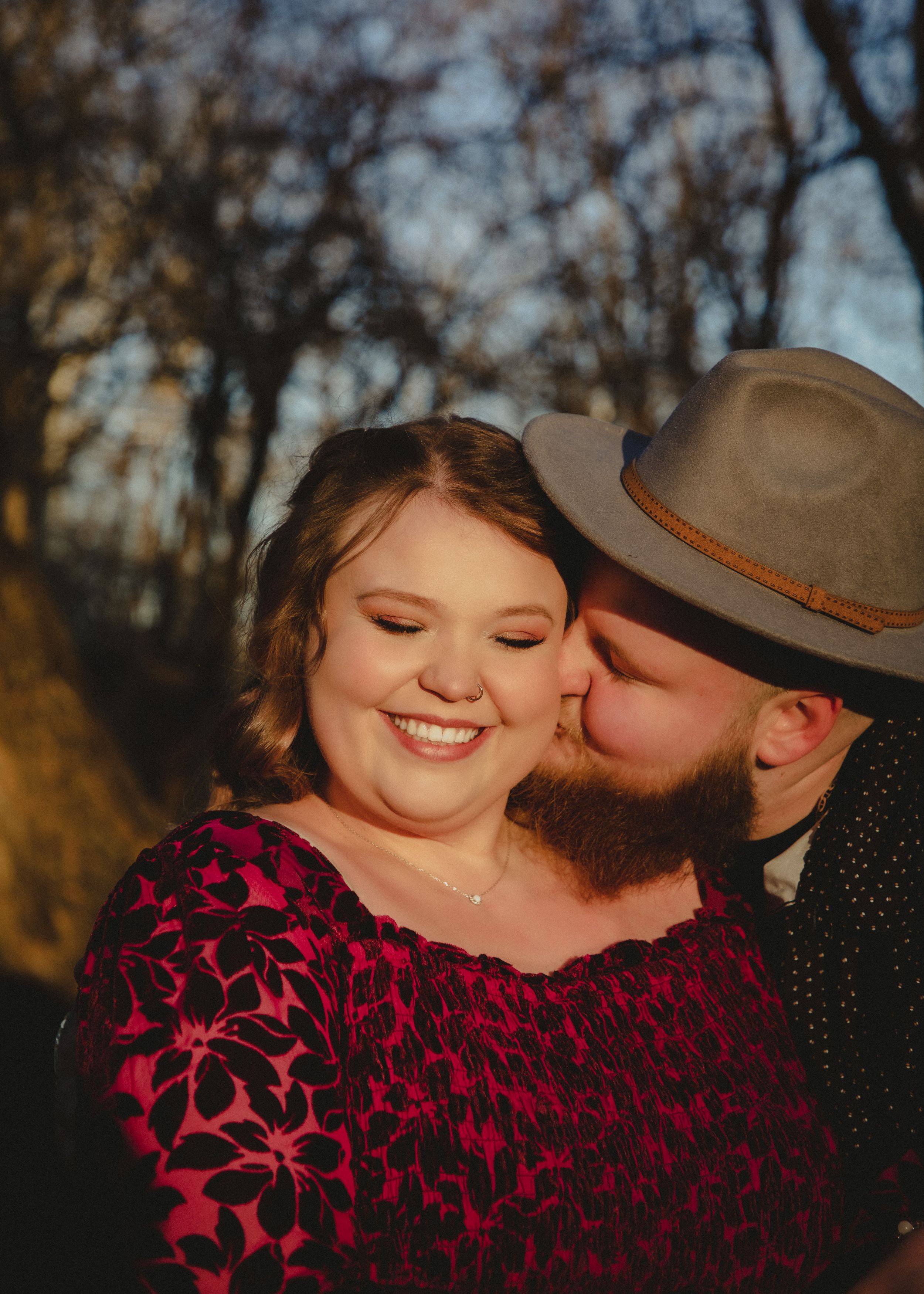 Romantic couple photos with burgundy velvet dress against golden sunset light.