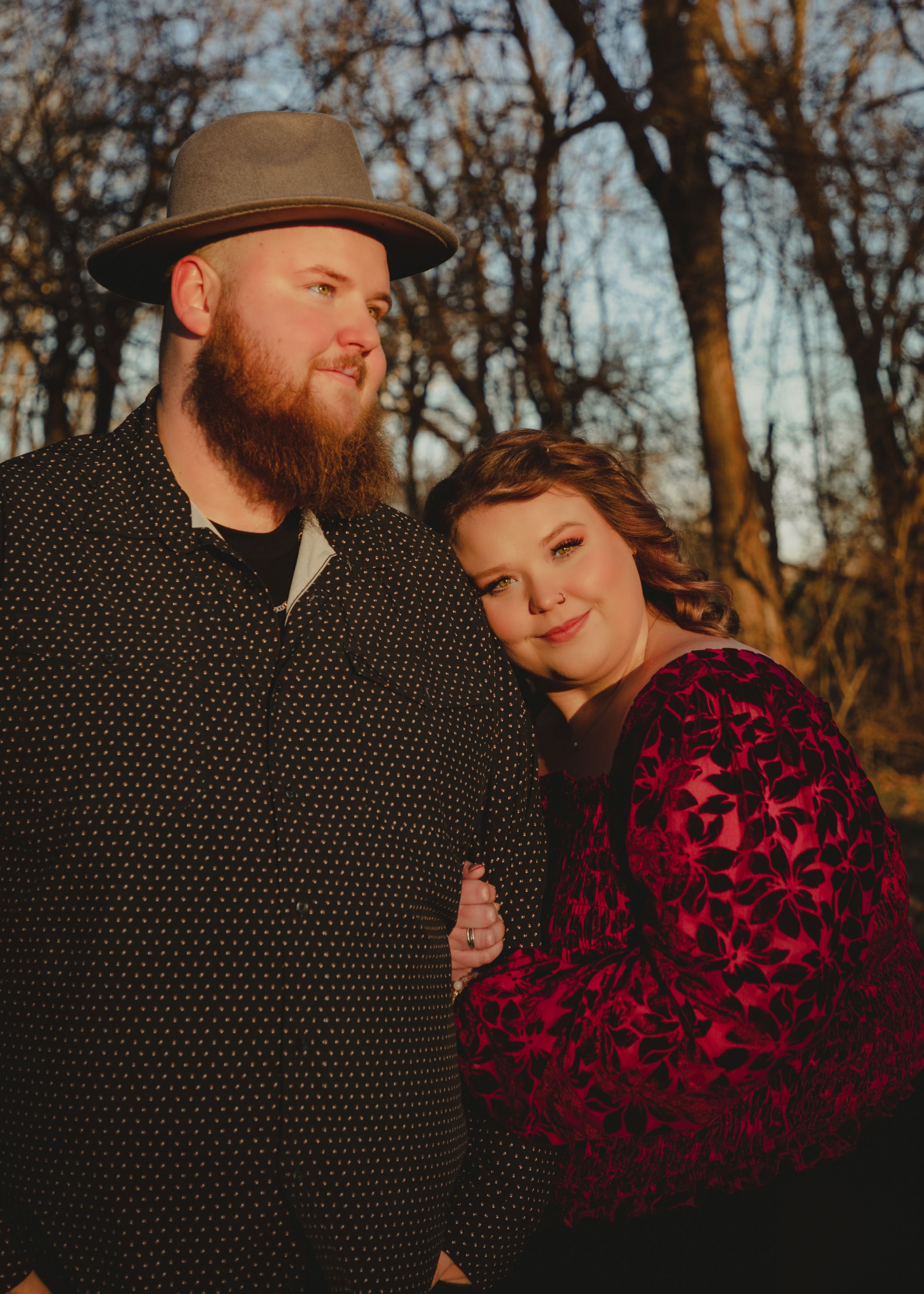 Romantic outdoor photoshoot featuring couple in burgundy dress and dotted shirt at golden hour.