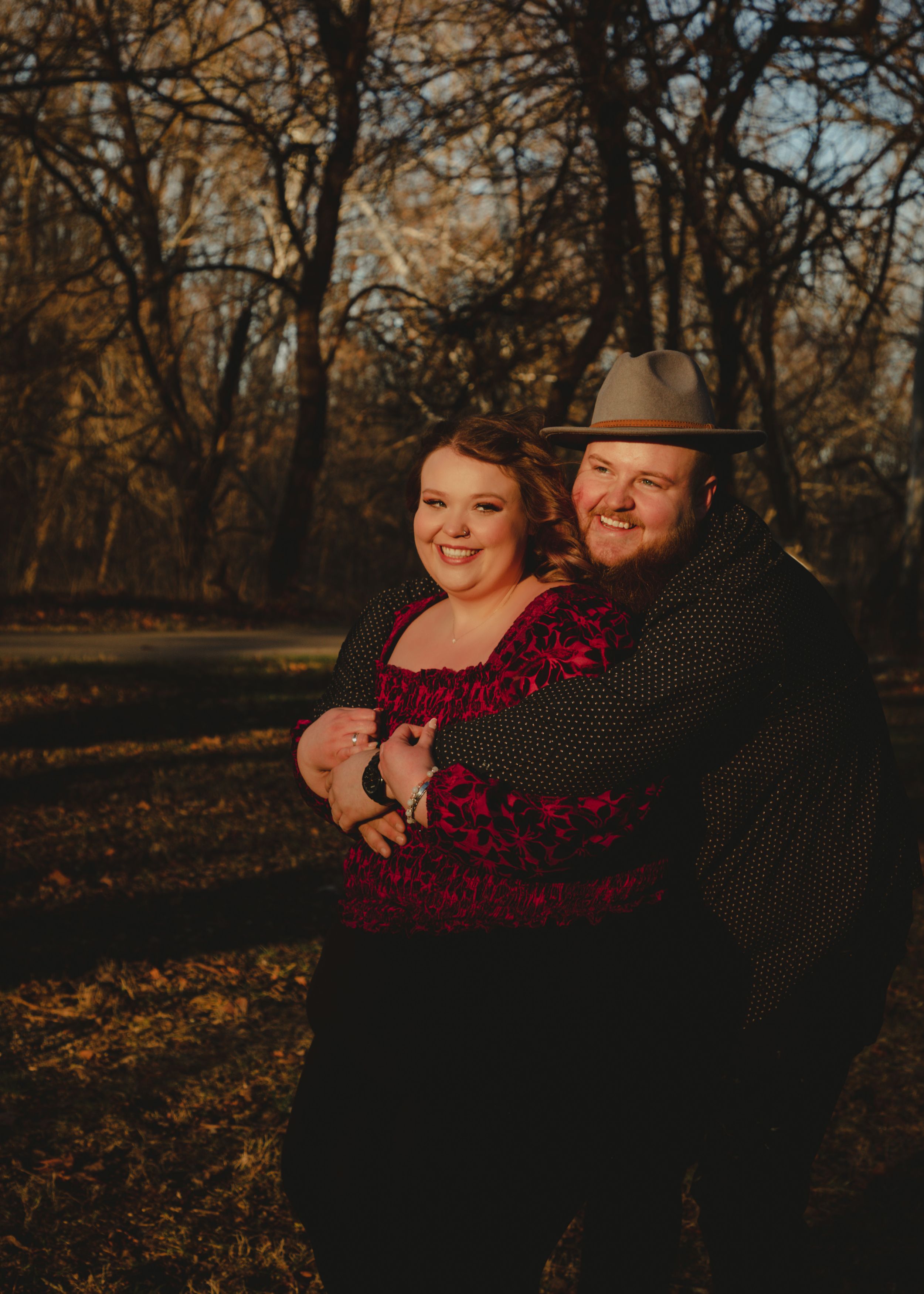 Couple sharing laughs during sunset photoshoot in autumn setting.