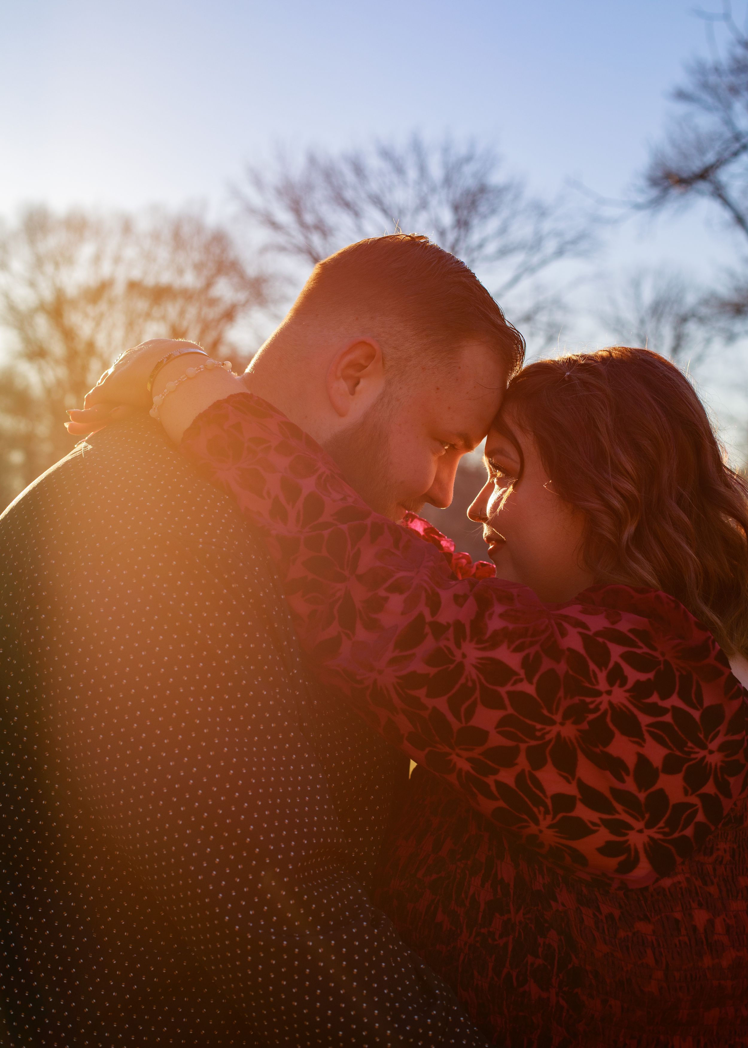 Romantic couple embraces during golden hour sunset in autumn forest setting.
