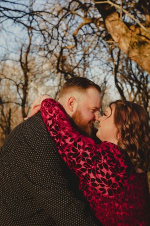 Intimate couple's portrait with polka dot and red floral patterns against autumn trees.