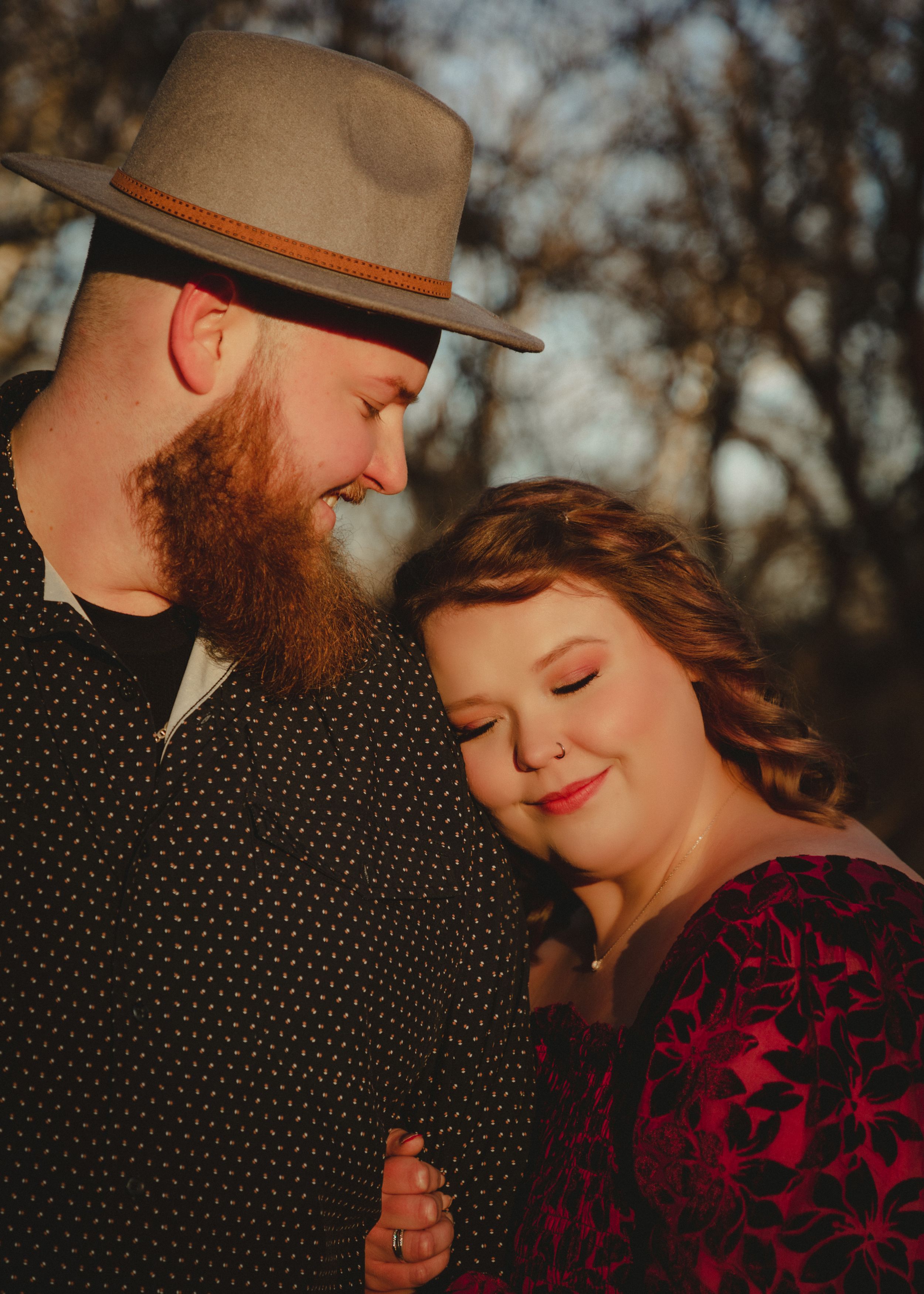 Intimate couple portraits with person in brown hat and burgundy velvet dress against autumn trees.