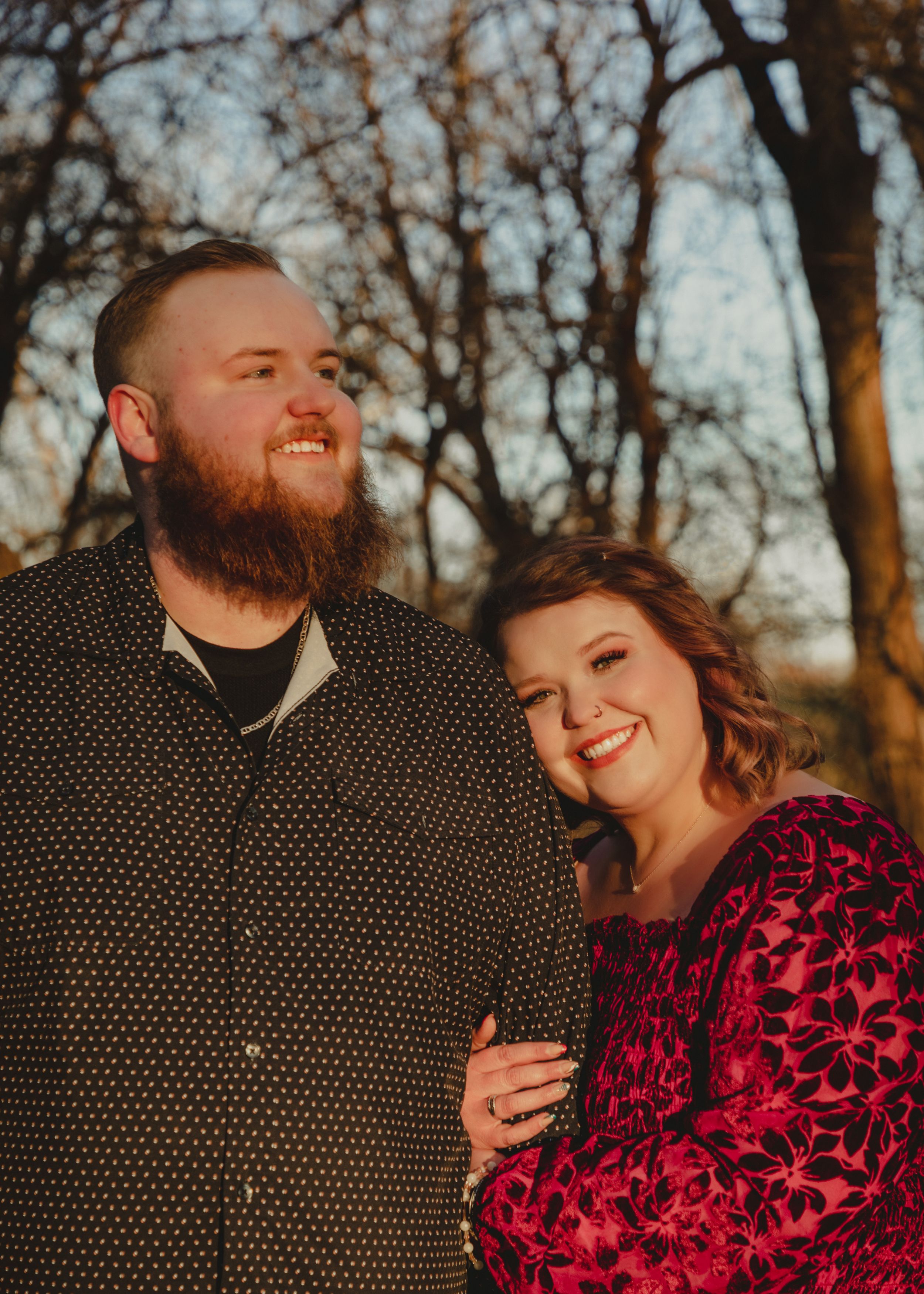 Couple in polka dot shirt and burgundy dress sharing intimate moments at sunset.