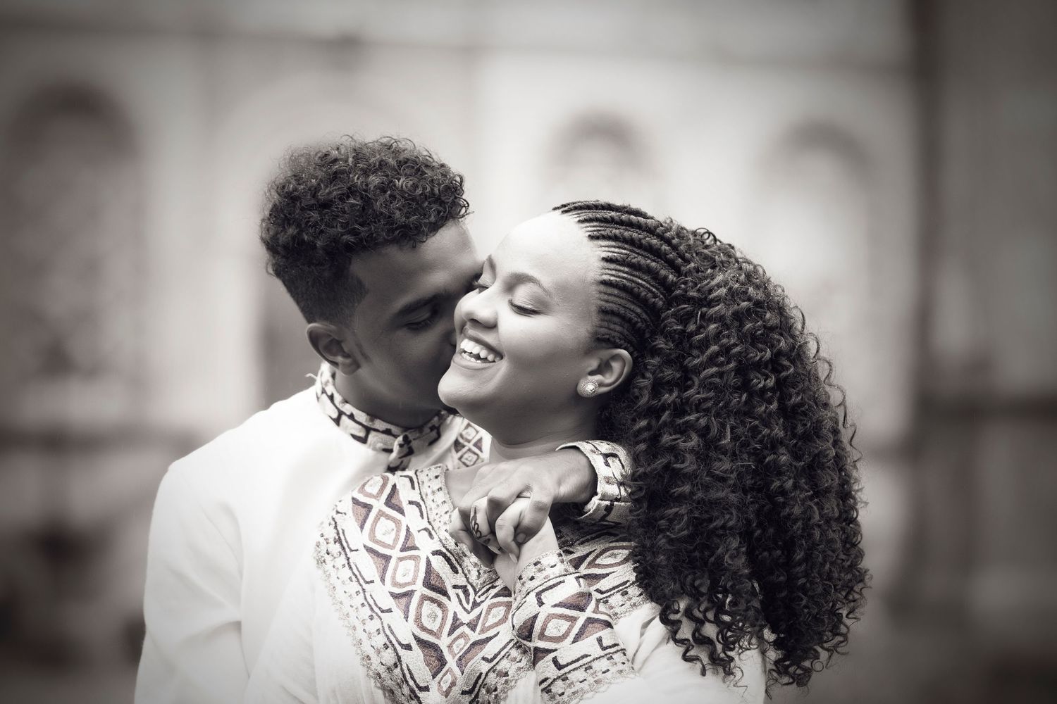 A romantic black and white portrait of a couple in traditional African attire.